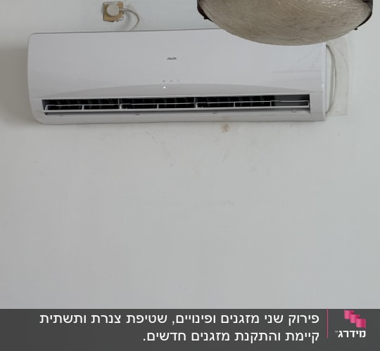 מזגן מותקן על קיר לבן ליד מנורה תלויה